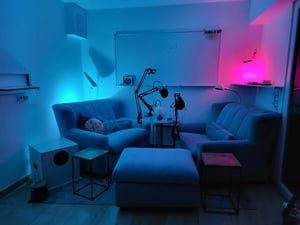 Sofamöbel und Hocker, dazwischen ein Tisch mit Podcast-Equipment