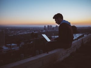 Mann_sitzt_auf_Mauer_mit_Laptop